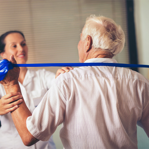 physical therapist coaching her senior patient through a resistance band exercise