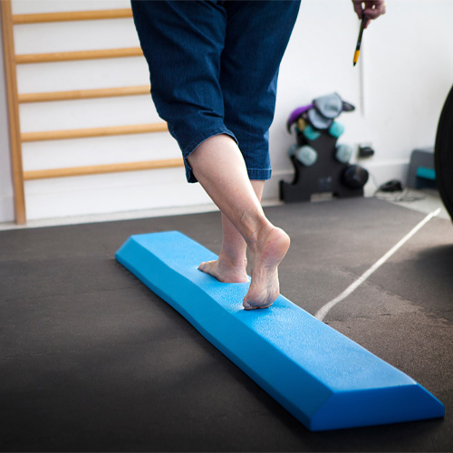 patient walks along a blue foam balance beam for a vestibular therapy exercise